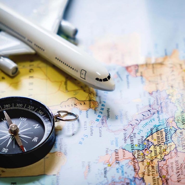 Avion, boussole et carte du monde. Le tourisme prend une dimension internationale.